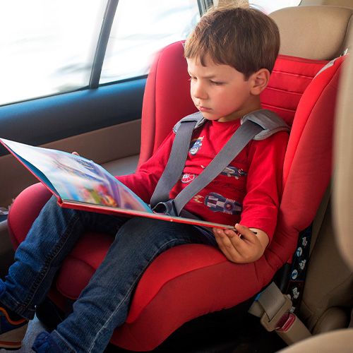niño viendo un libro en el carro